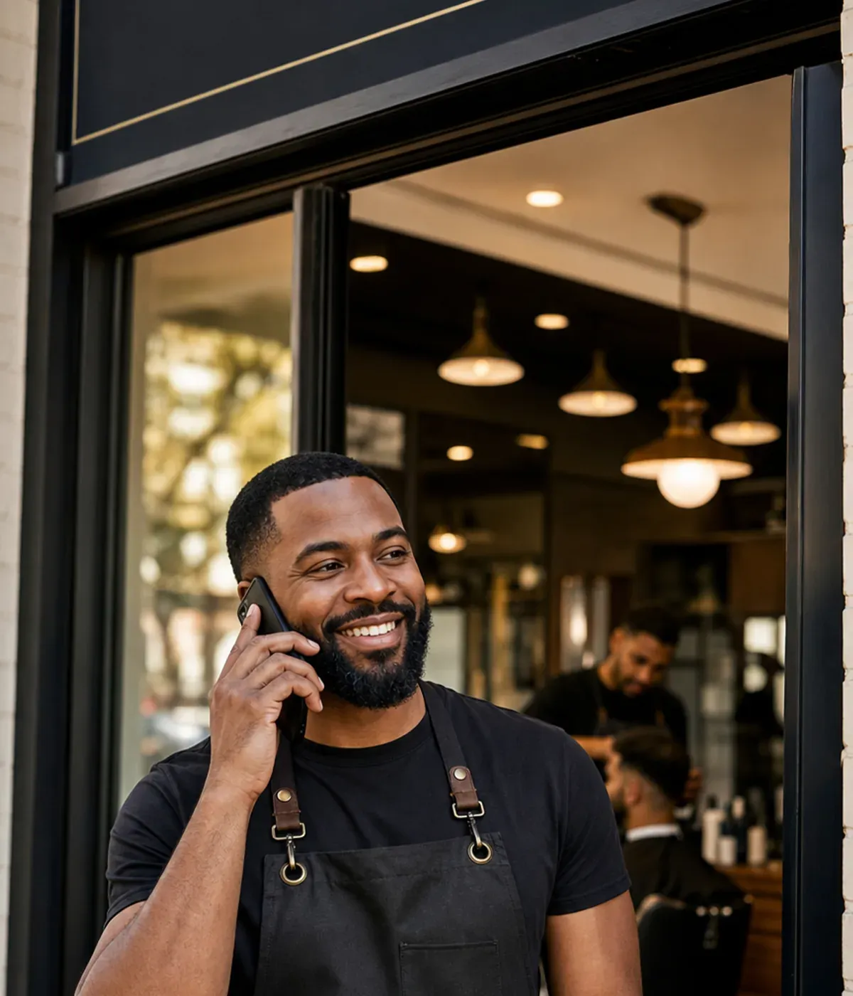 Small business owner smiling while taking a phone call at his shop